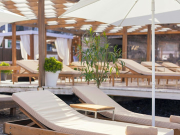 Пара шезлонгов под зонтом целый день